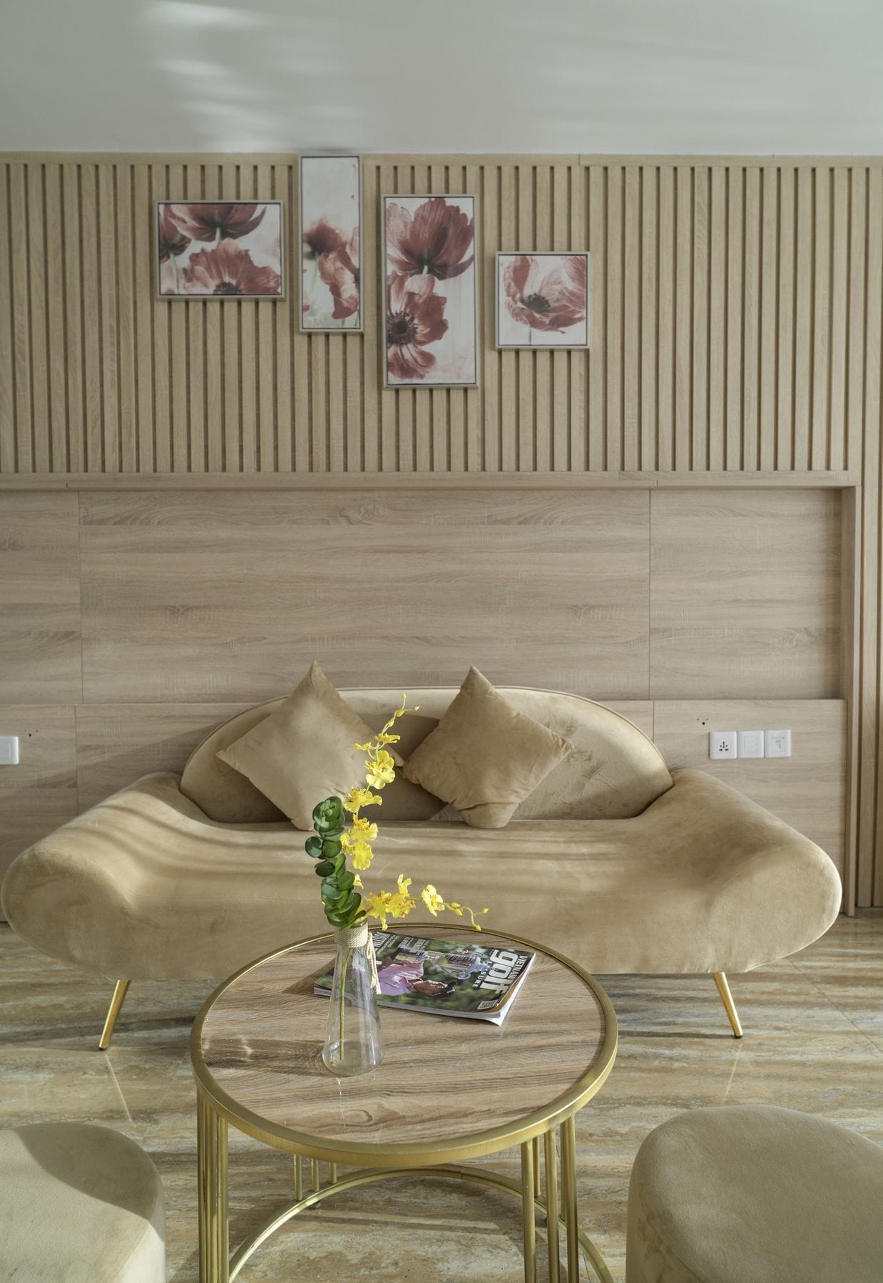 Un saló modern amb un sofà, una taula de centre rodona amb una revista, i un ram de flors en un vas.