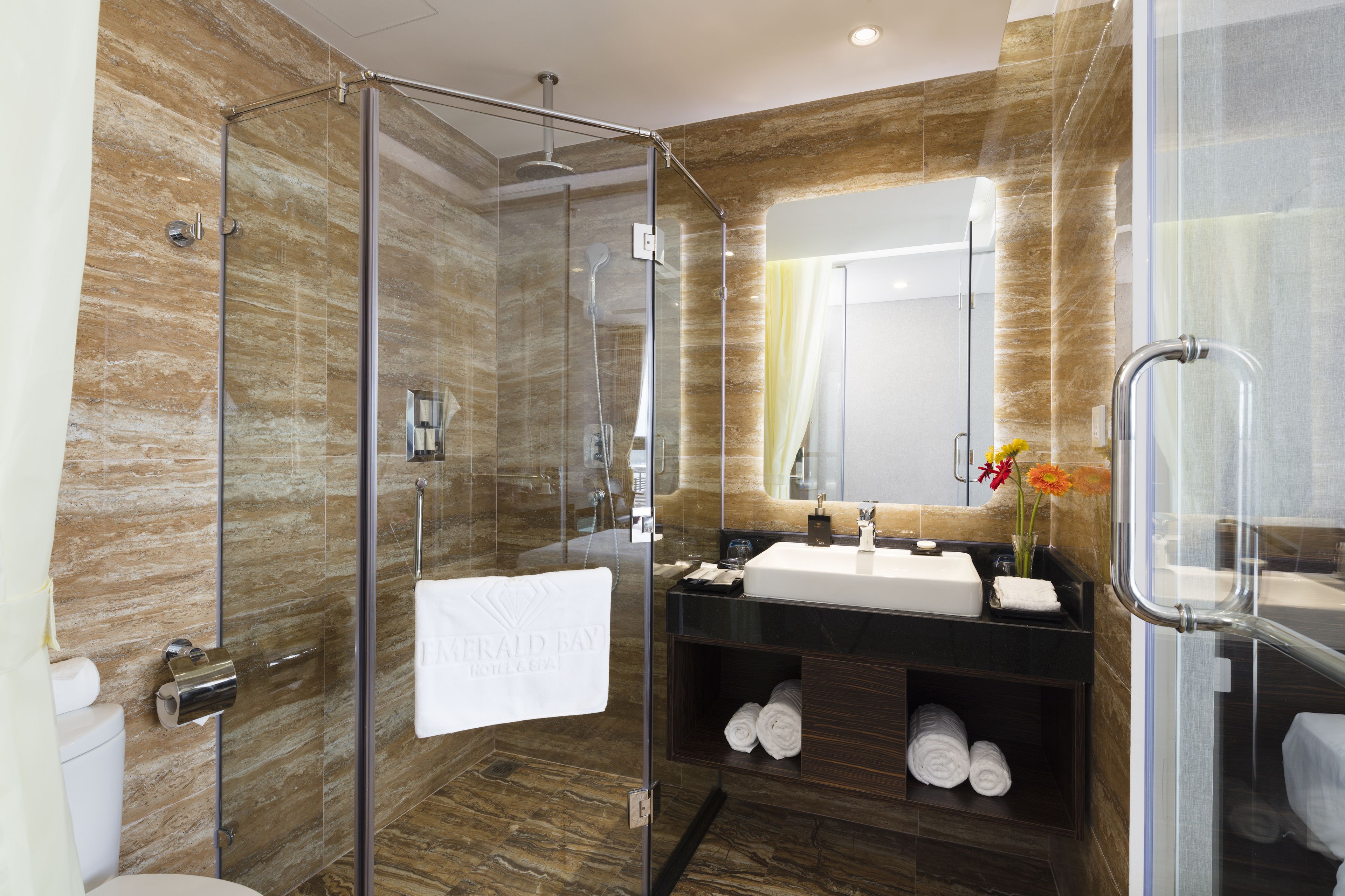 A modern bathroom with a glass-enclosed shower, a vanity with a mirror, and a towel rack.
