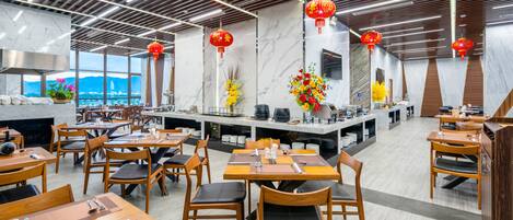 A modern restaurant with wooden tables and chairs, marble walls, and red lanterns.