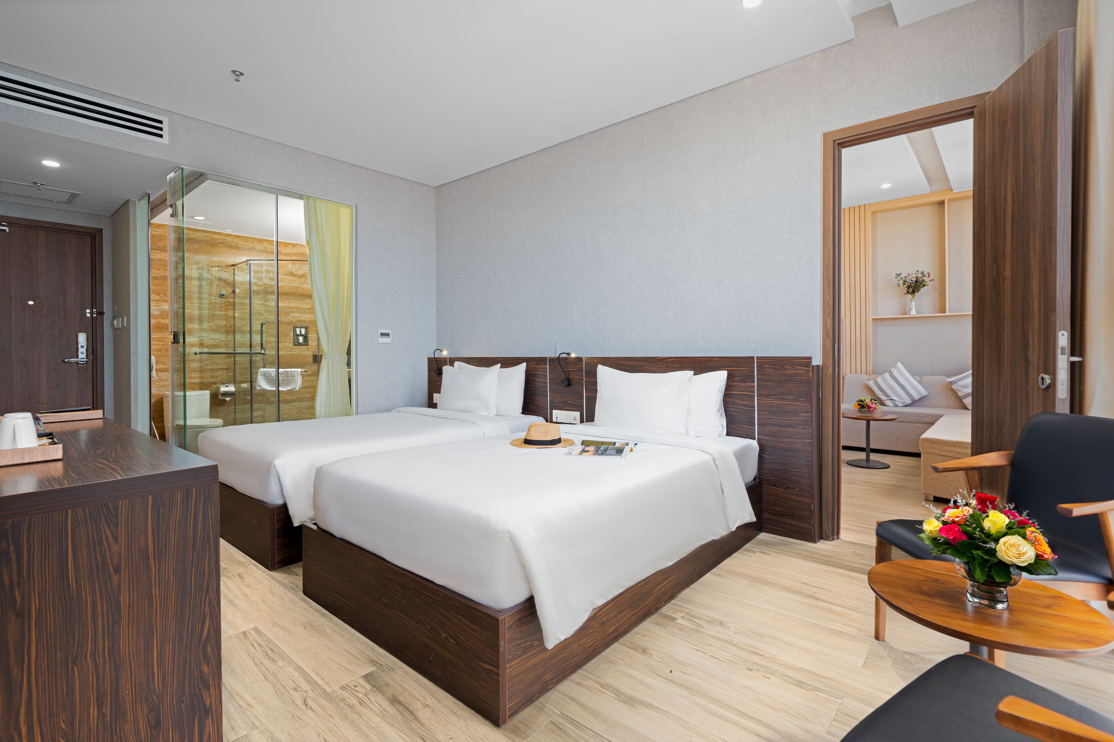 A hotel room with a large bed, a desk, a chair, and a small table with flowers.