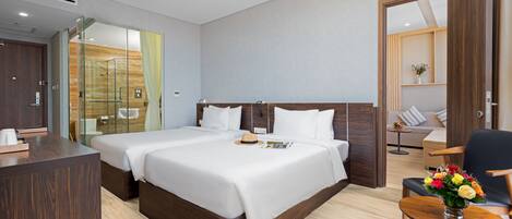A hotel room with a large bed, a desk, a chair, and a small table with flowers.