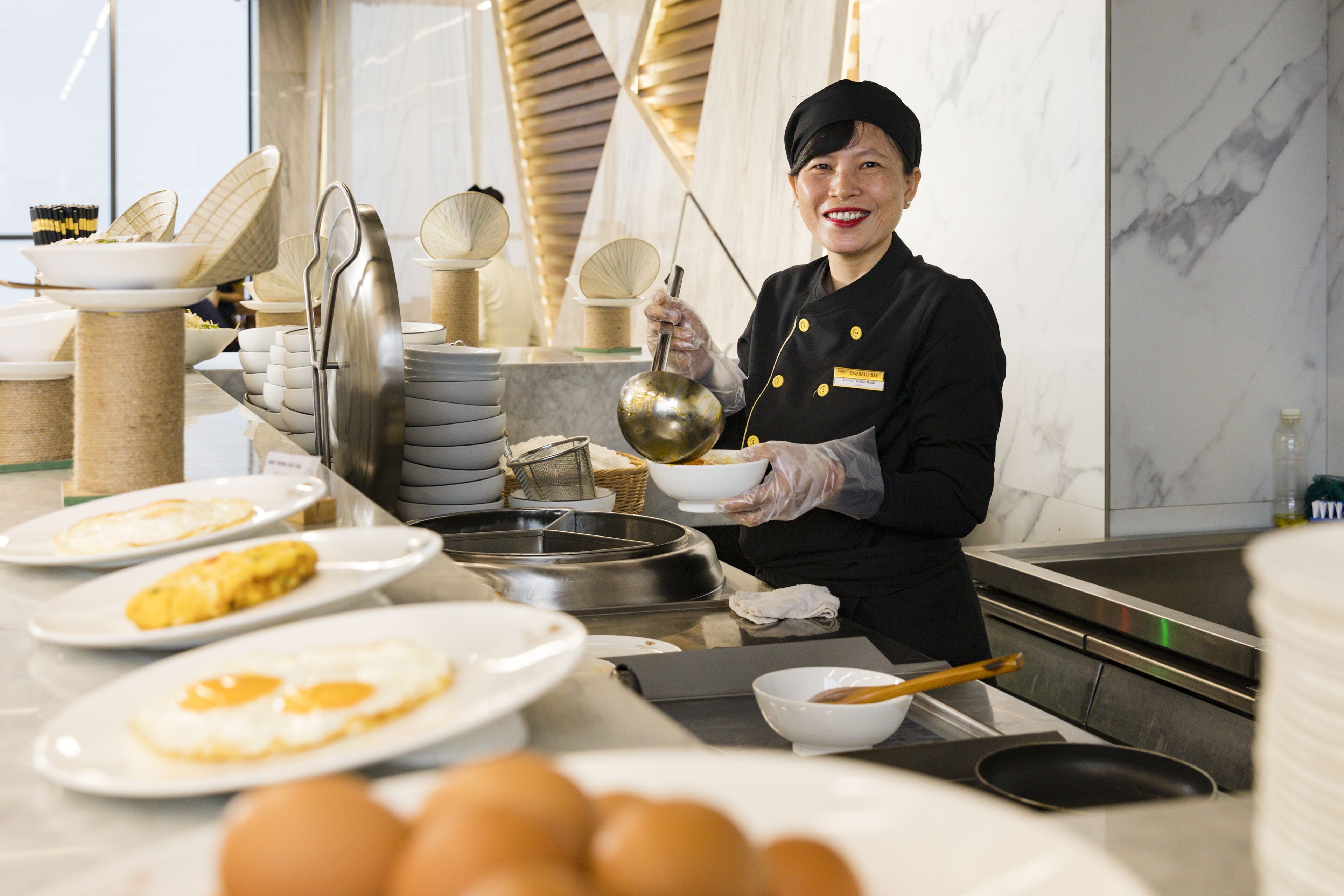 A kitchen area with a chef preparing food, including a bowl and a pan on the counter.
