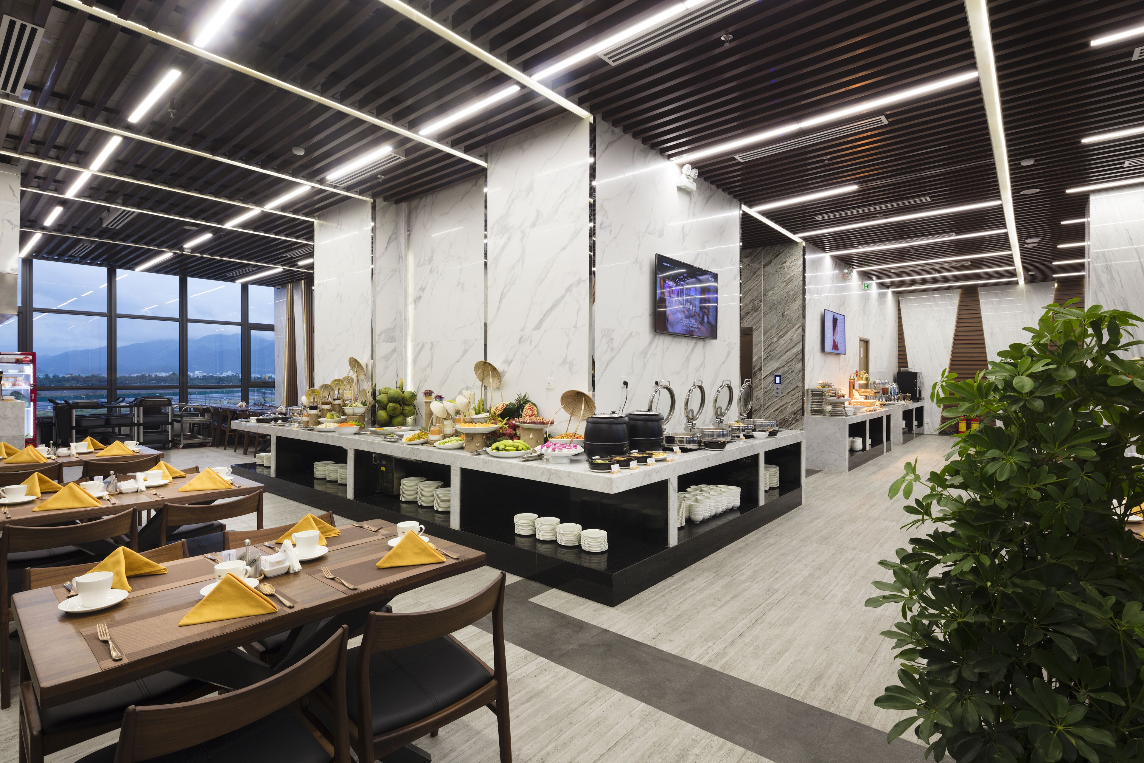 Ein modernes Restaurant mit Marmorwand, einem Buffet und Blick auf die Berge.
