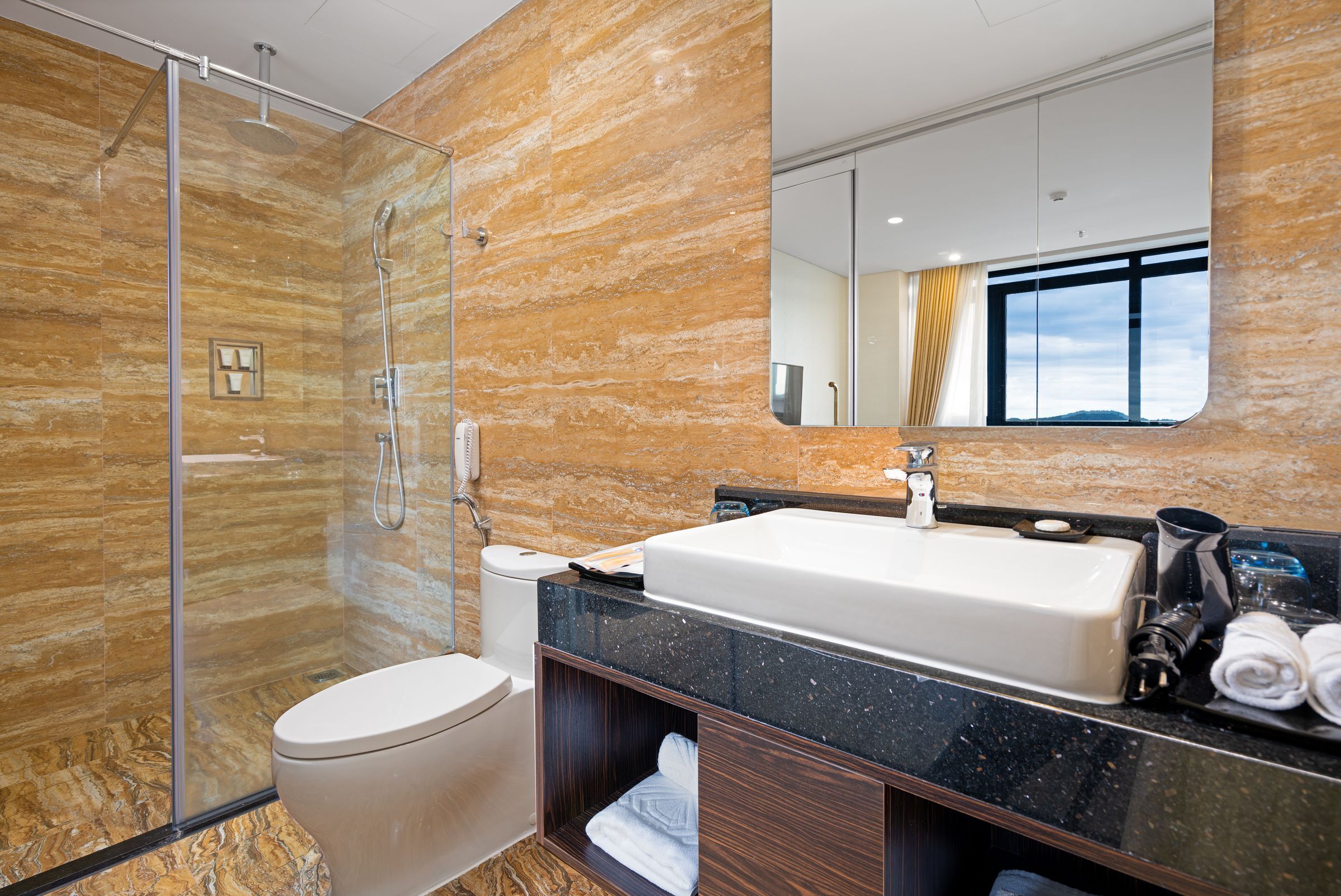 A modern bathroom with a glass-enclosed shower, a white toilet, a large sink, and a mirror above the sink.