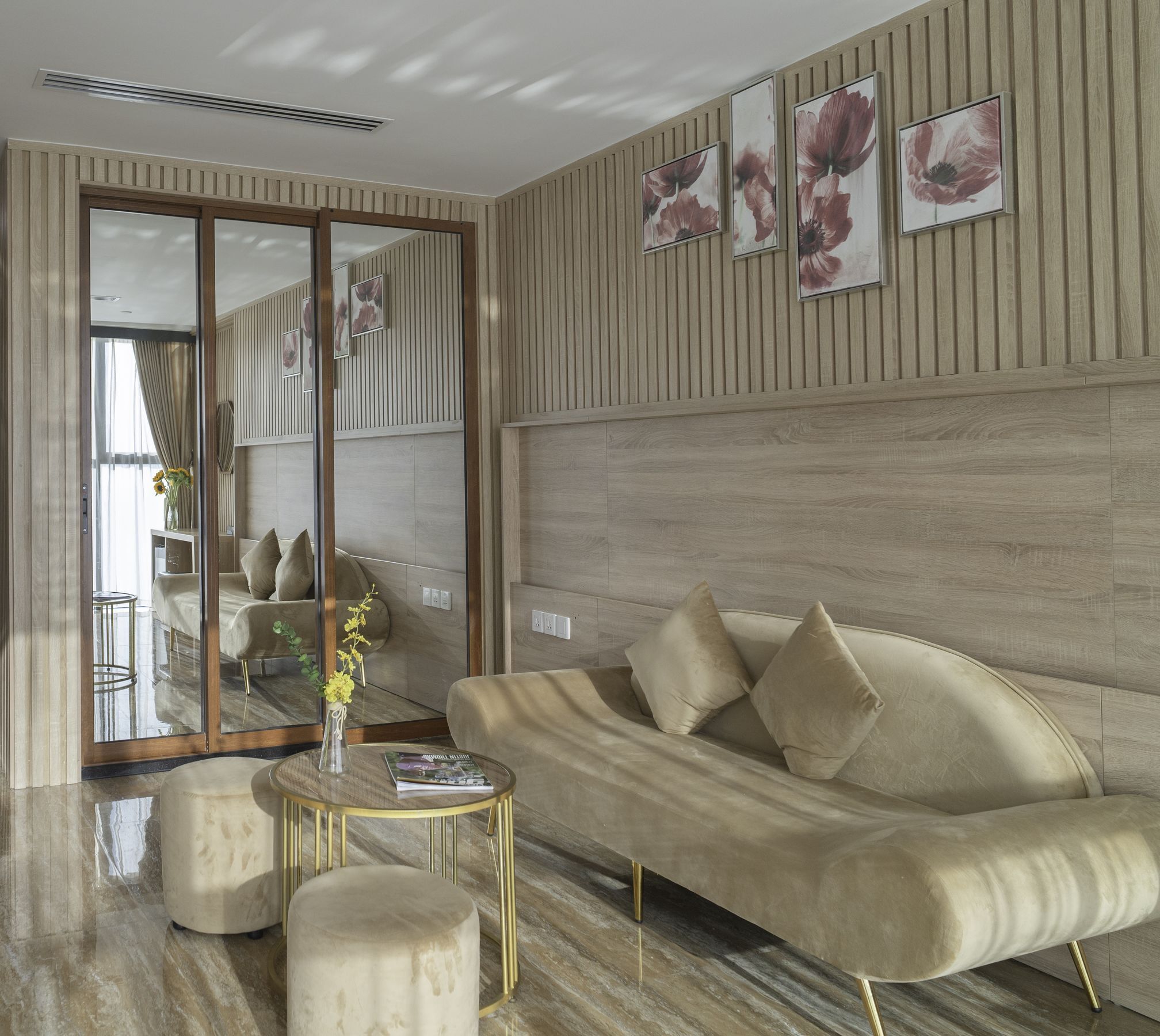A modern living room with a sofa, coffee table, and a mirror reflecting the room.