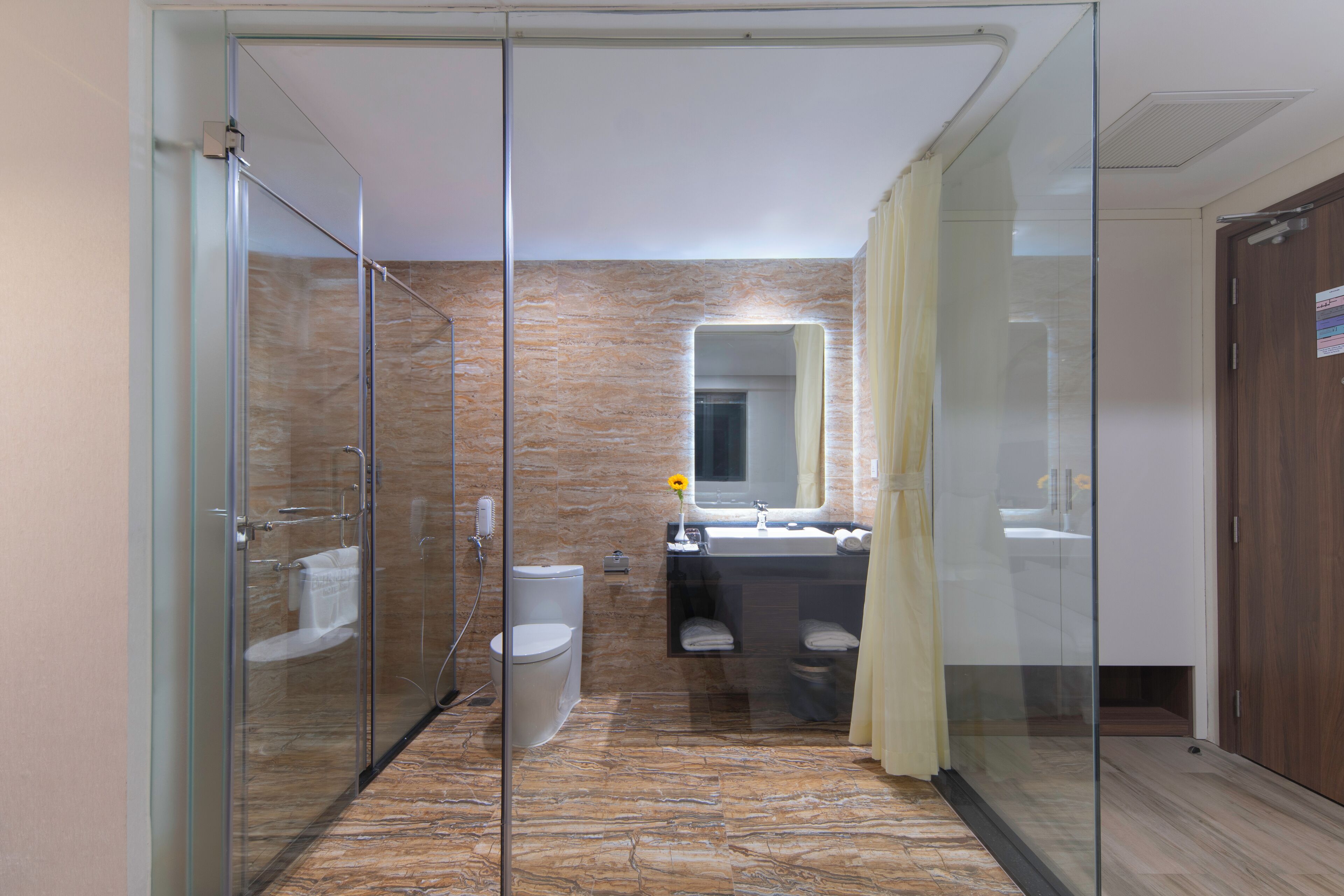 A modern bathroom with a glass shower enclosure, a toilet, a sink, and a mirror.