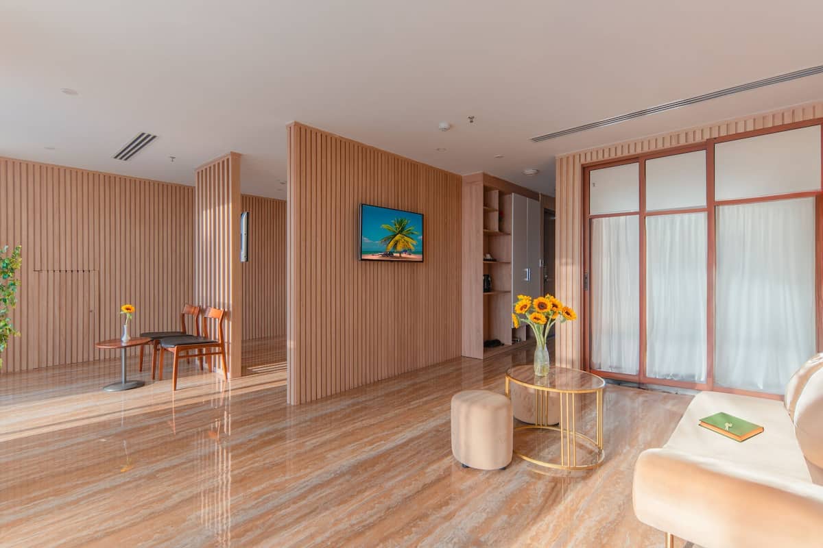 Eine moderne Hotelhalle mit Holzwandverkleidung, Marmorboden, einem Gemälde mit Strandmotiv, einer Vase mit Sonnenblumen und einem Ledersofa.