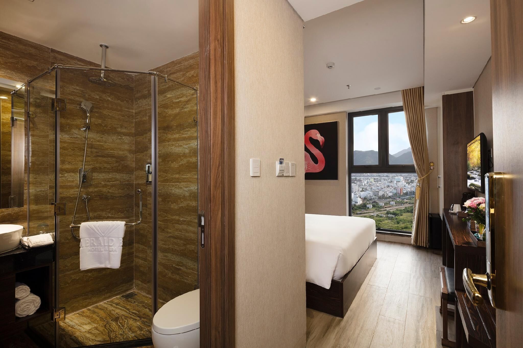 Un baño de hotel moderno con ducha de mampara de vidrio, inodoro y lavamanos.
