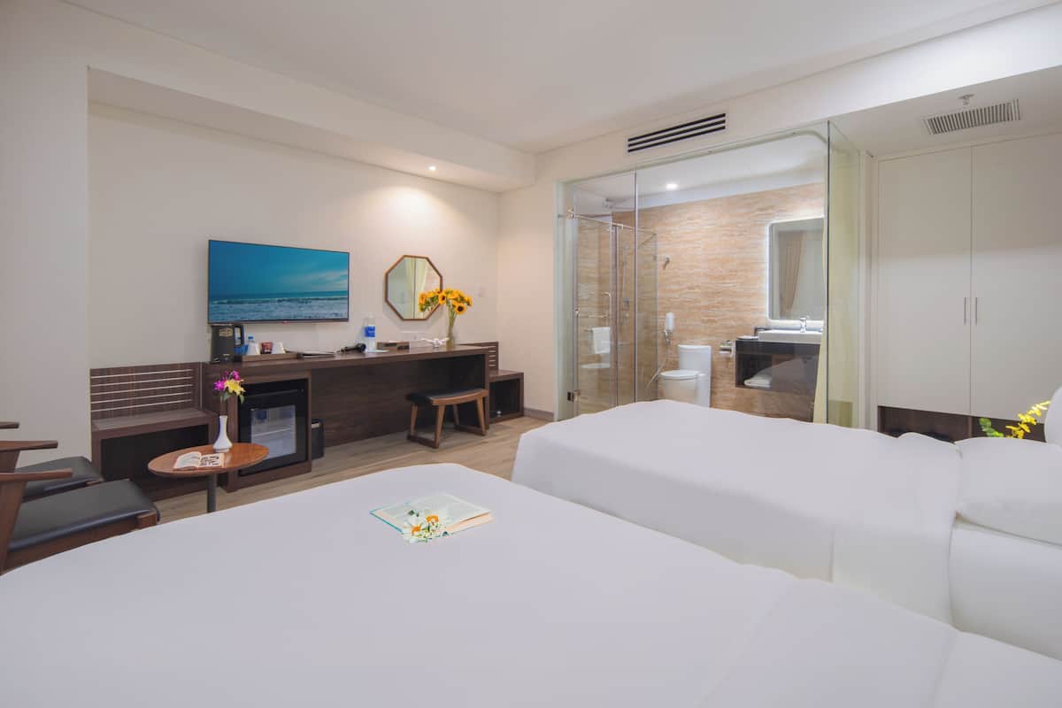 Ein Hotelzimmer mit zwei Betten, einem Schreibtisch mit Stuhl, einem Fernseher, einem Kamin und einem Badezimmer mit Duschkabine.