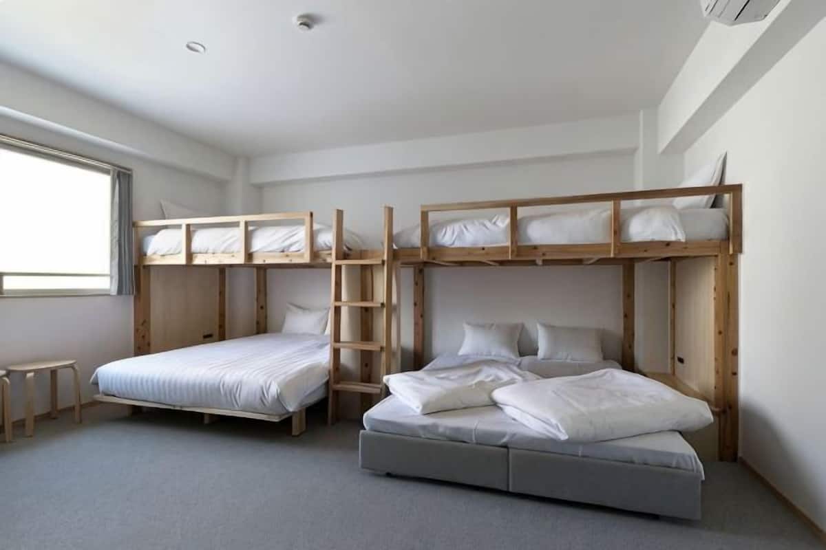 Une chambre avec des lits superposés, un bureau et une fenêtre.