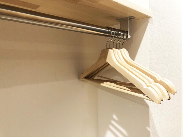 A wooden coat rack with multiple hangers against a wall. - DD HOTEL NAKASU (Fukuoka)