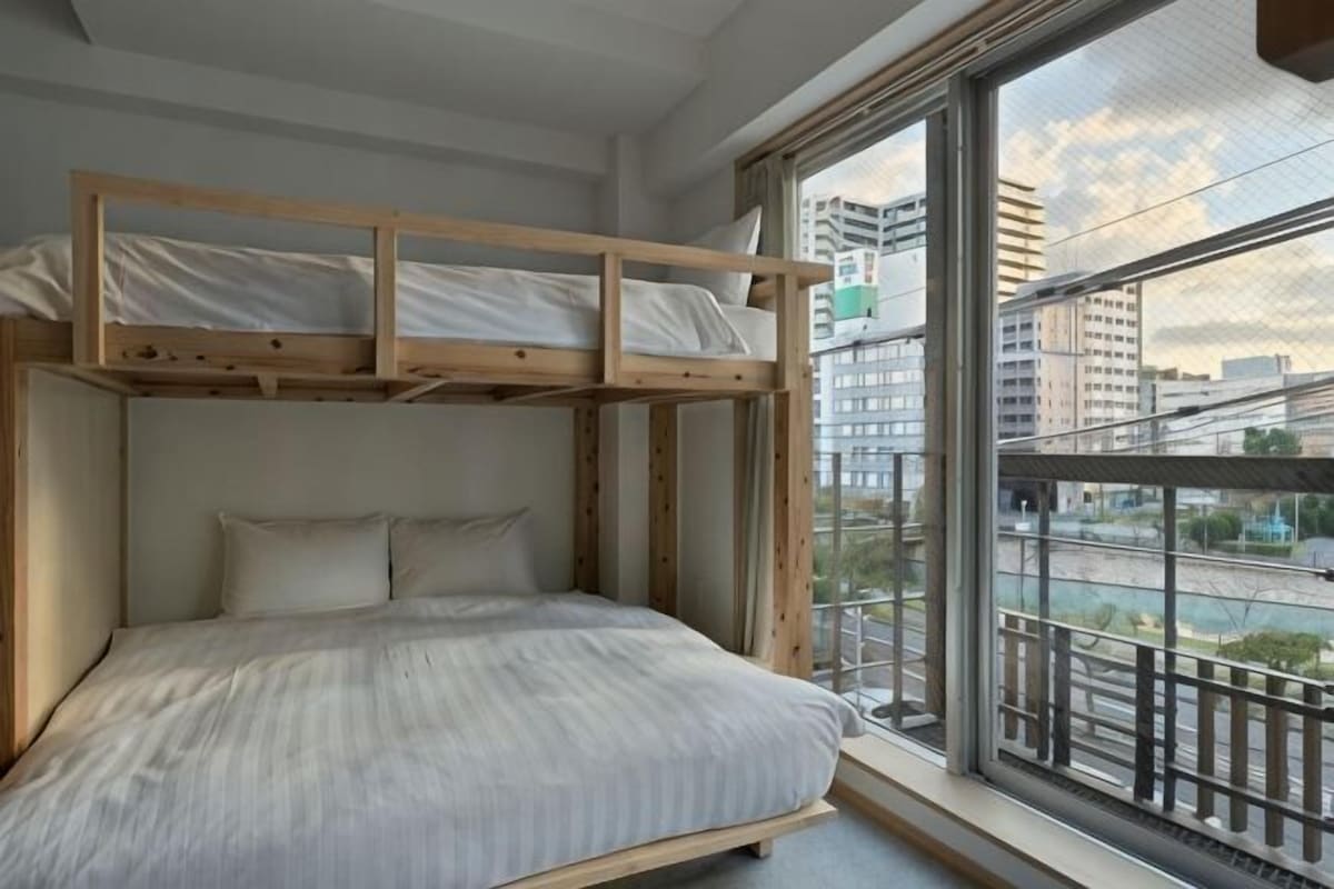 A bunk bed with a view of a cityscape through a large window.