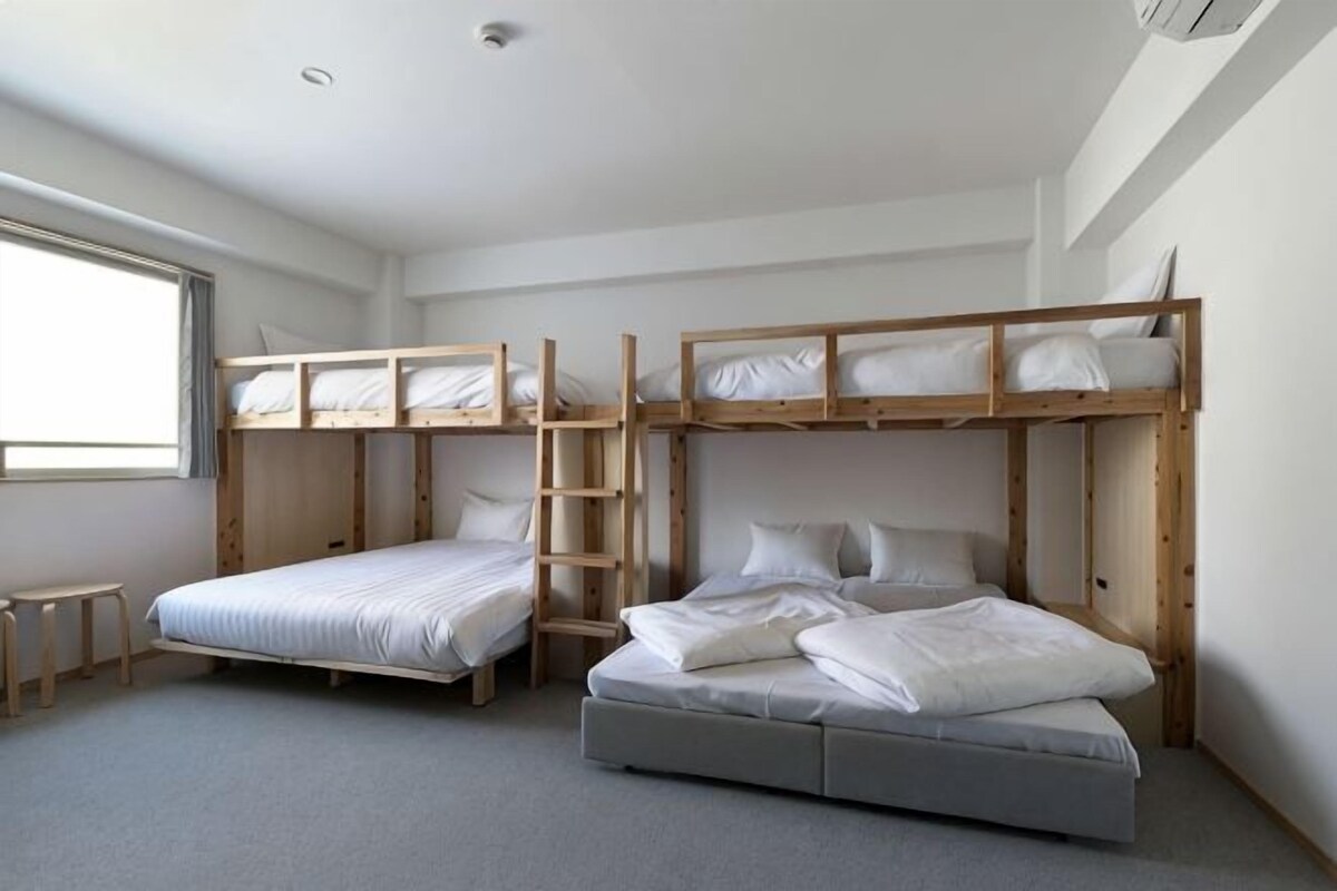 Ein Zimmer mit Etagenbetten, einem Schreibtisch und einem Fenster.