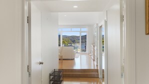 A hallway leading to a balcony with a view of a lake and hills.