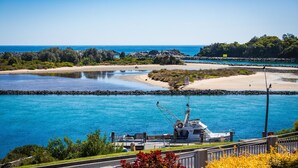 A marina with boats docked, a sandy beach, and a rocky shoreline.