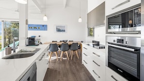 Une cuisine moderne dotée d’un îlot central, d’appareils électroménagers intégrés et d’un coin repas avec des chaises.