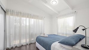 Une chambre à coucher avec un lit, une lampe de chevet et des rideaux légers.