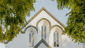 Un bâtiment blanc doté de fenêtres en arc de cercle et d’un fronton triangulaire.
