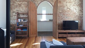 Un salon avec un mur en briques, des meubles en bois, une bibliothèque, un téléviseur et un coin salon confortable.