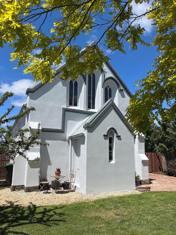 A church with a white exterior, a bell tower, and a small porch with potted plants.