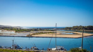 A marina with boats docked, a clear sky, and a calm sea. - Grand Pacific 2 Unit 2 - Ground Floor (NAROOMA)