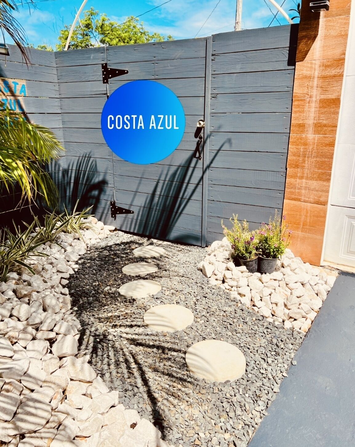 Una entrada con puerta y un letrero circular azul que dice "COSTA AZUL".