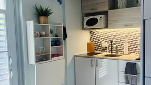 A modern kitchen with white cabinets, a microwave, a sink, and a wooden countertop. - Costa Azul Suite  (Aguadilla)