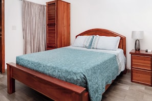 A bedroom with a wooden bed, a bedside table, a lamp, and a wardrobe.