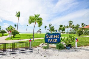 A sign reading "Sunset Park" with a beach view in the background.