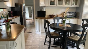 A kitchen with white cabinetry, a dining table with chairs, a refrigerator, and a microwave. - Close to Parris Island! Beaufort SC,  Newly Renovated 2 Bedroom 2 Bath Sleeps 6 (Beaufort)