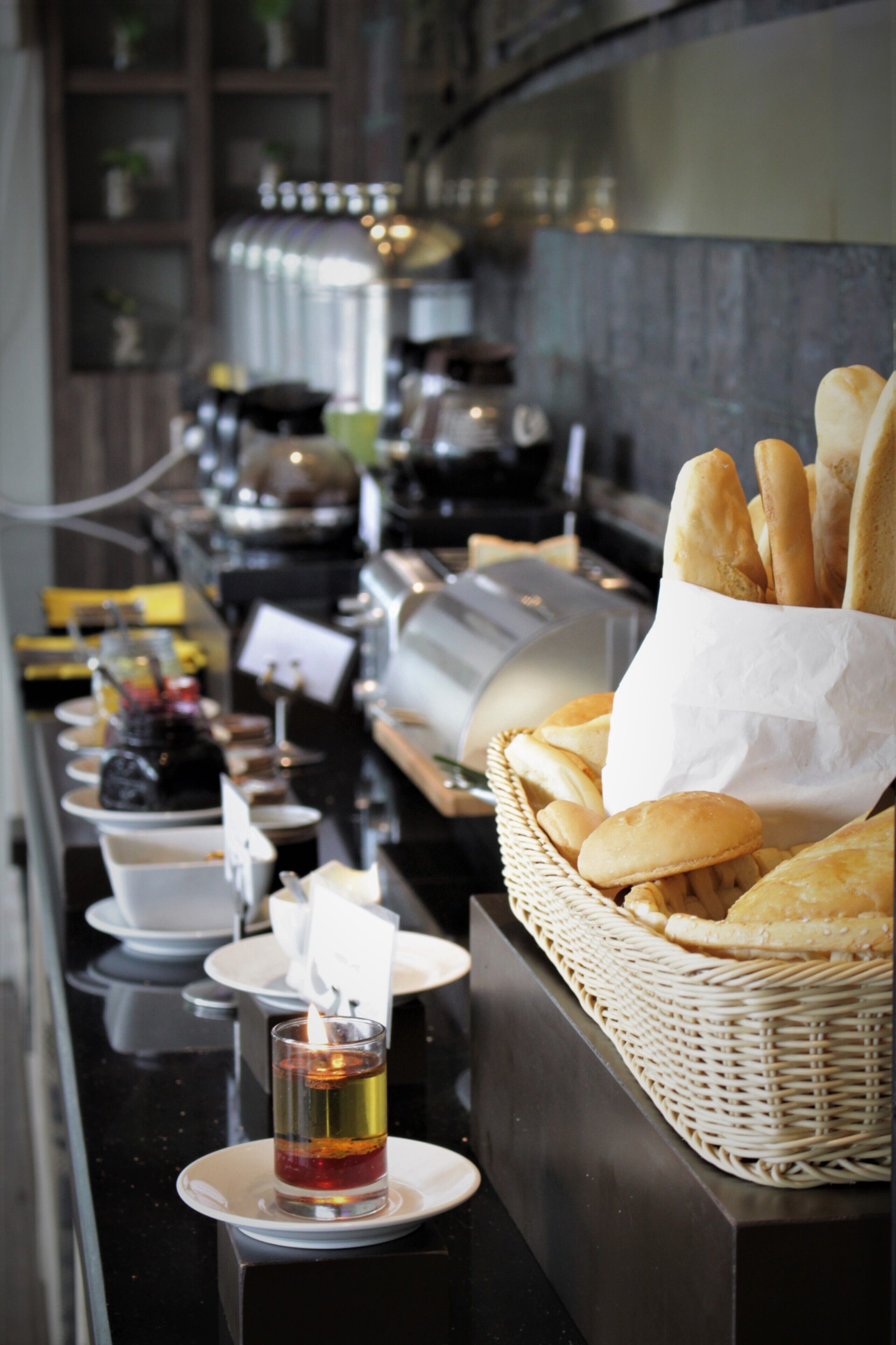 A buffet setup with bread, a drink, and various dishes.