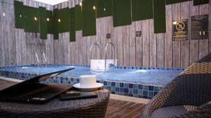 Un área de spa con una bañera de hidromasaje, sillas de descanso y una computadora portátil sobre una mesa.