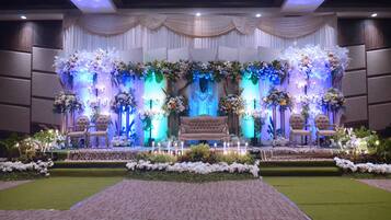 A stage with a bench, chairs, and floral arrangements.