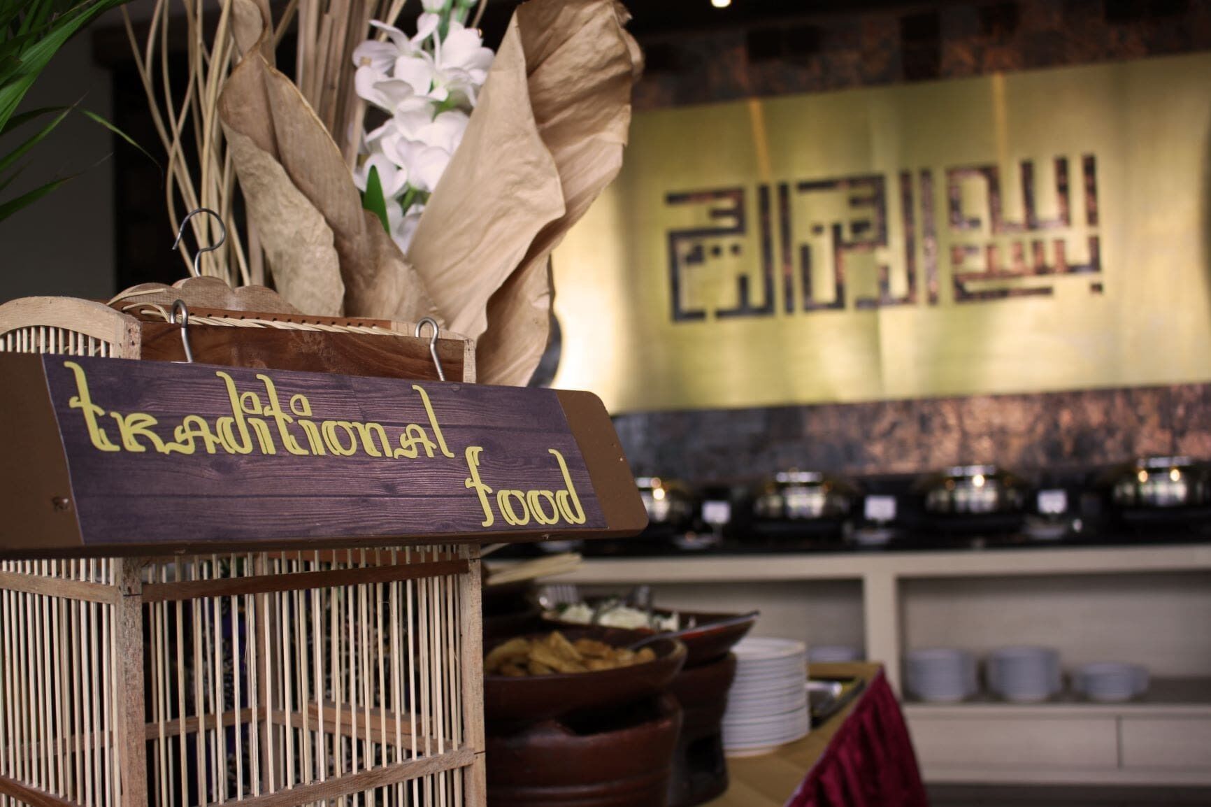 A traditional food sign in a rustic setting with a wooden sign and a basket of dried plants.