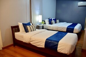 Una cama doble con cubrecama azul y blanco, un cabecero de madera y dos almohadas.