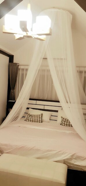 Una cama con dosel, una mesita de noche y una lámpara fijada a la pared.