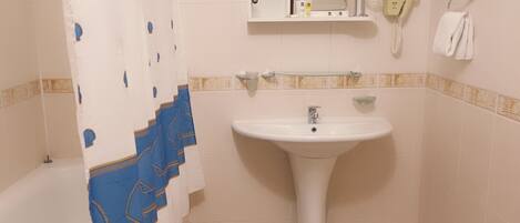 A bathroom with a white sink, a glass shelf, a towel rack, and a shower curtain.