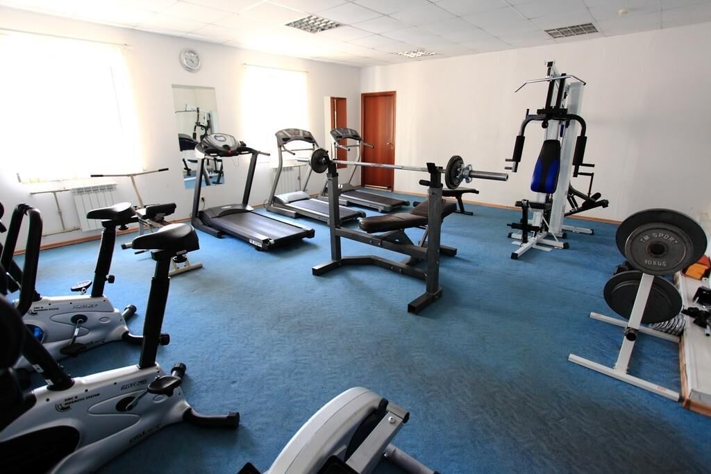 A gym with various exercise equipment including treadmills, stationary bikes, and weight machines.