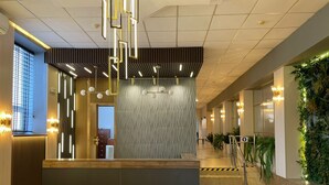 Ein moderner Empfangsbereich mit einem Holzbüro, einer strukturierten Wand und einer Treppe zu einer oberen Etage.