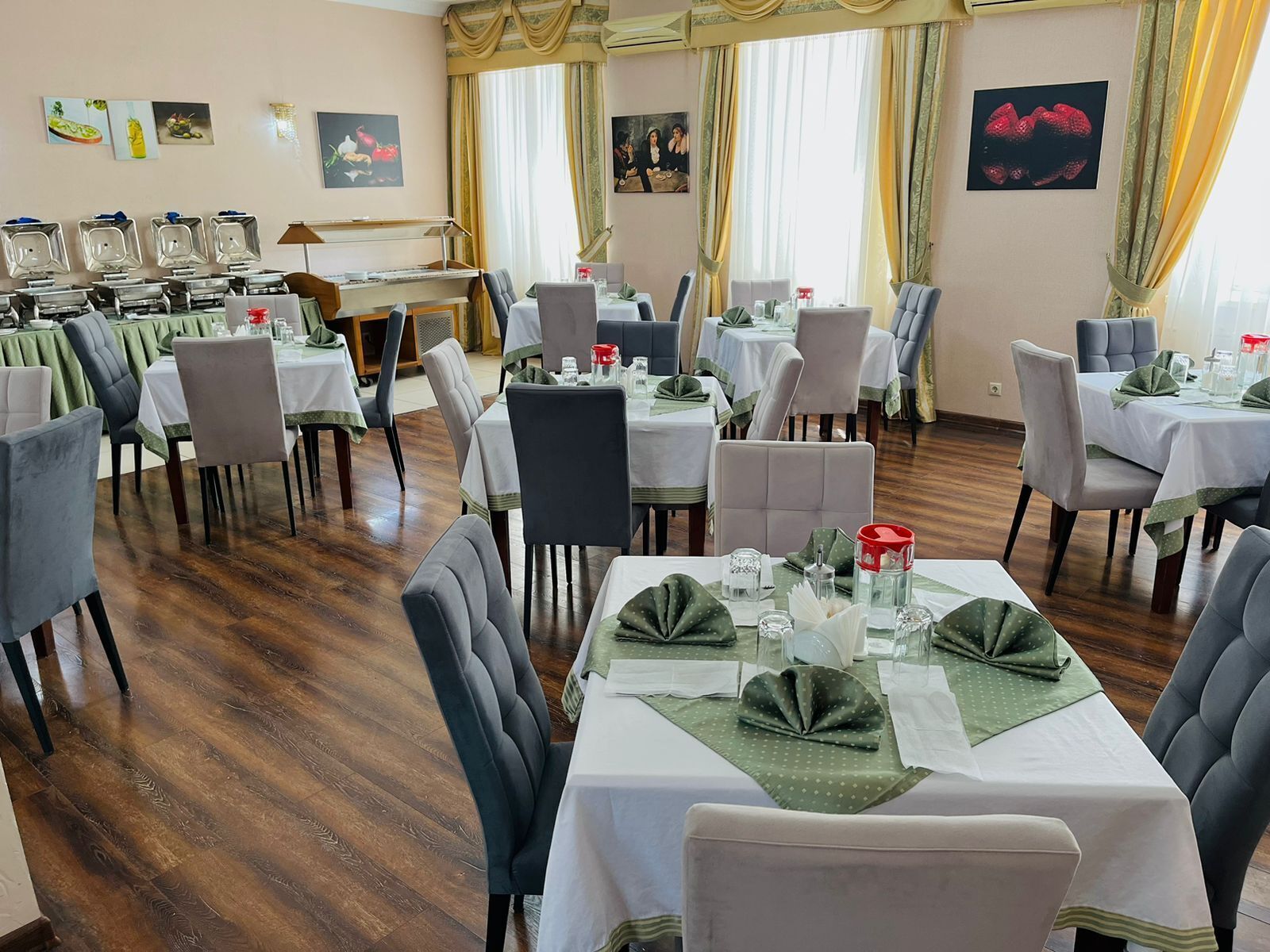 Un espace repas comprenant plusieurs tables et chaises, un piano et des œuvres d’art accrochées aux murs.