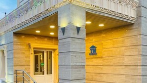 Ein Hotelzugang mit einer prachtvollen Treppe, einer großen Säule und einem Schild mit dem Hotelnamen.