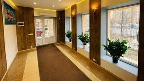 Ein Hotelgang mit Holzwandverkleidung, Teppichboden und Blumentöpfen an den Fenstern.