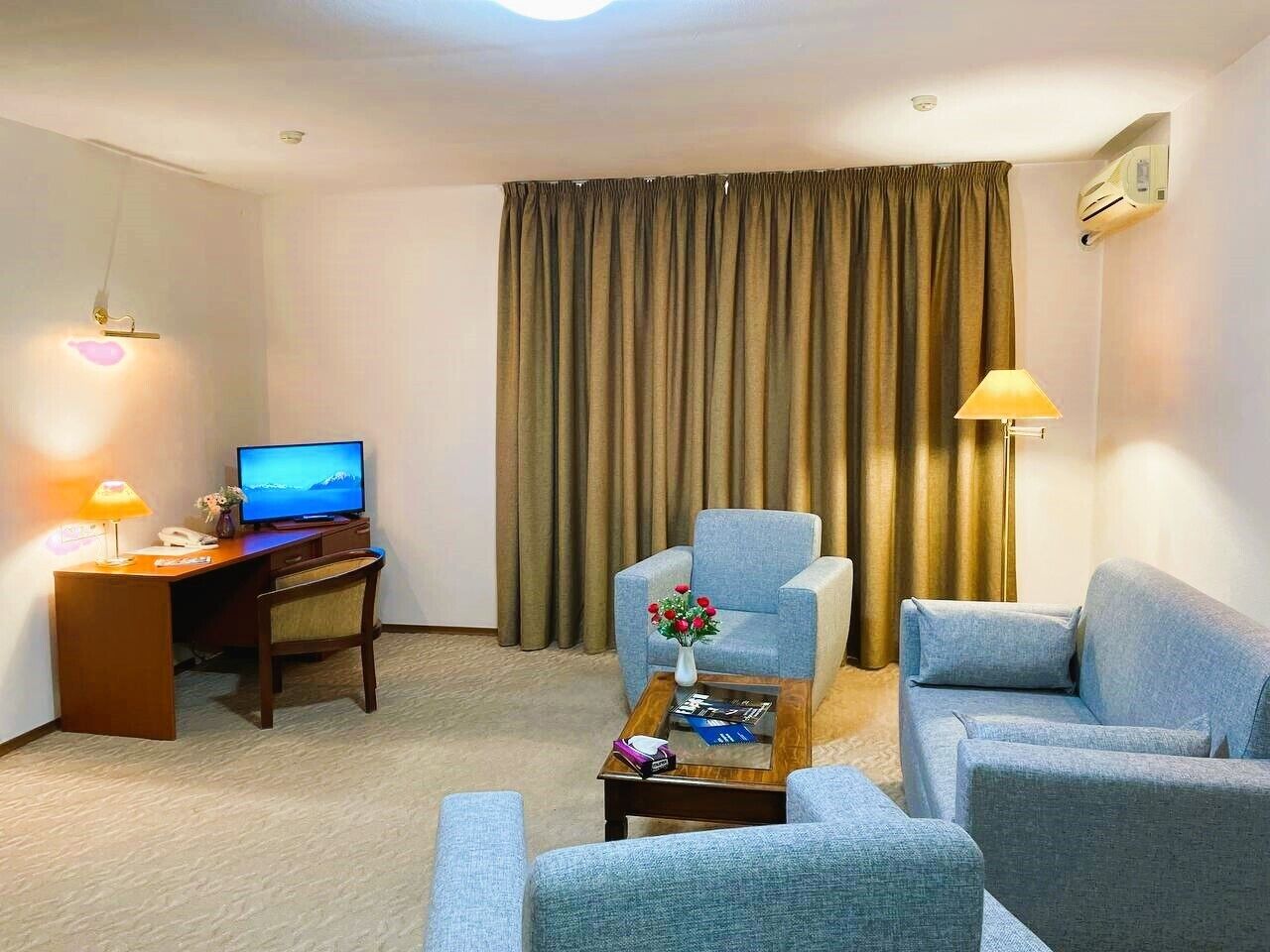 Une chambre d’hôtel équipée d’un bureau, d’une télévision, d’un canapé et d’un fauteuil.