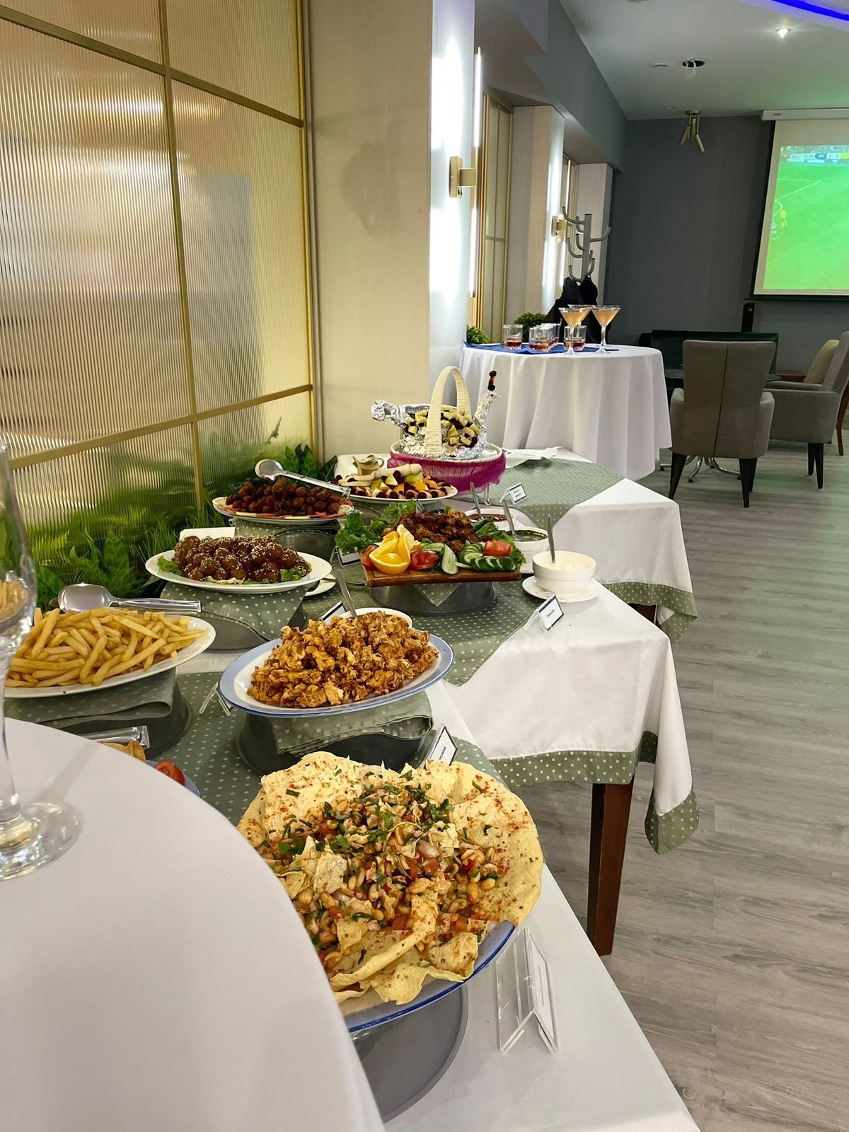 Ett bord med en bufféuppställning med olika rätter, en projektorduk i bakgrunden och en sittgrupp med stolar.