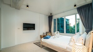 Quarto de hotel moderno com uma cama grande, TV fixada na parede e uma janela com cortinas.