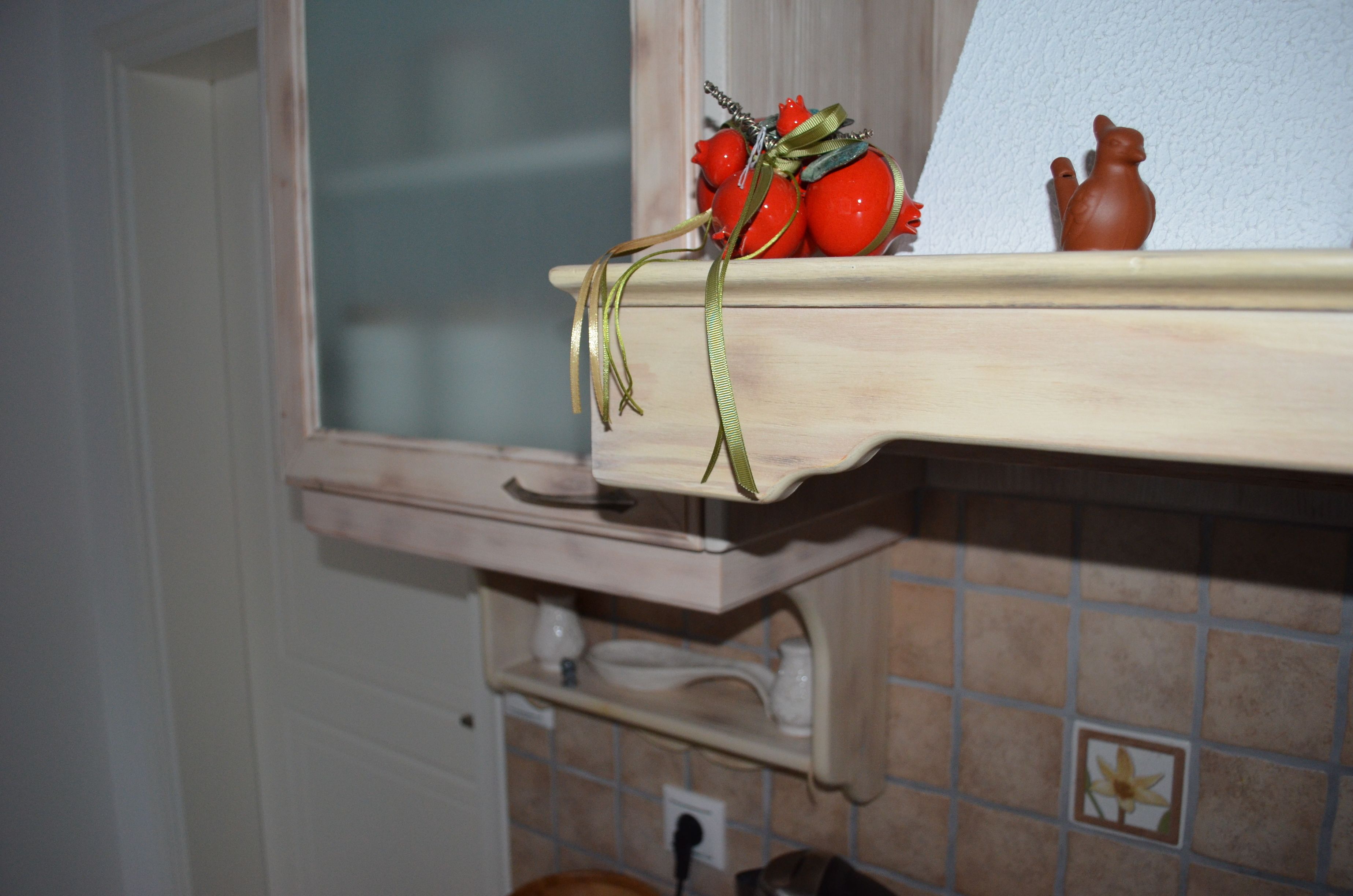 Un estante de cocina con adornos, entre ellos tomates y una figurita.