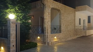A stone building with a gated entrance, illuminated by wall lights and a central light fixture.