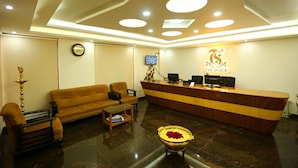 A reception area with a wooden reception desk, a sofa, a coffee table, and a decorative bowl with flowers. - Hotel The Shack (Bengaluru)