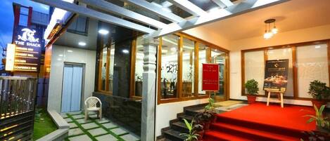 A hotel entrance with a red carpet, glass doors, and a sign for 'The Shack' restaurant.