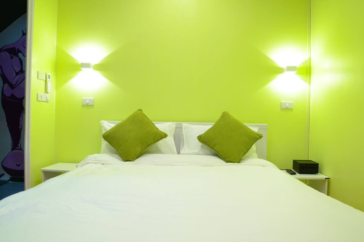 Ein Zimmer mit einem Bett, grünen Wänden und zwei Wandleuchten.